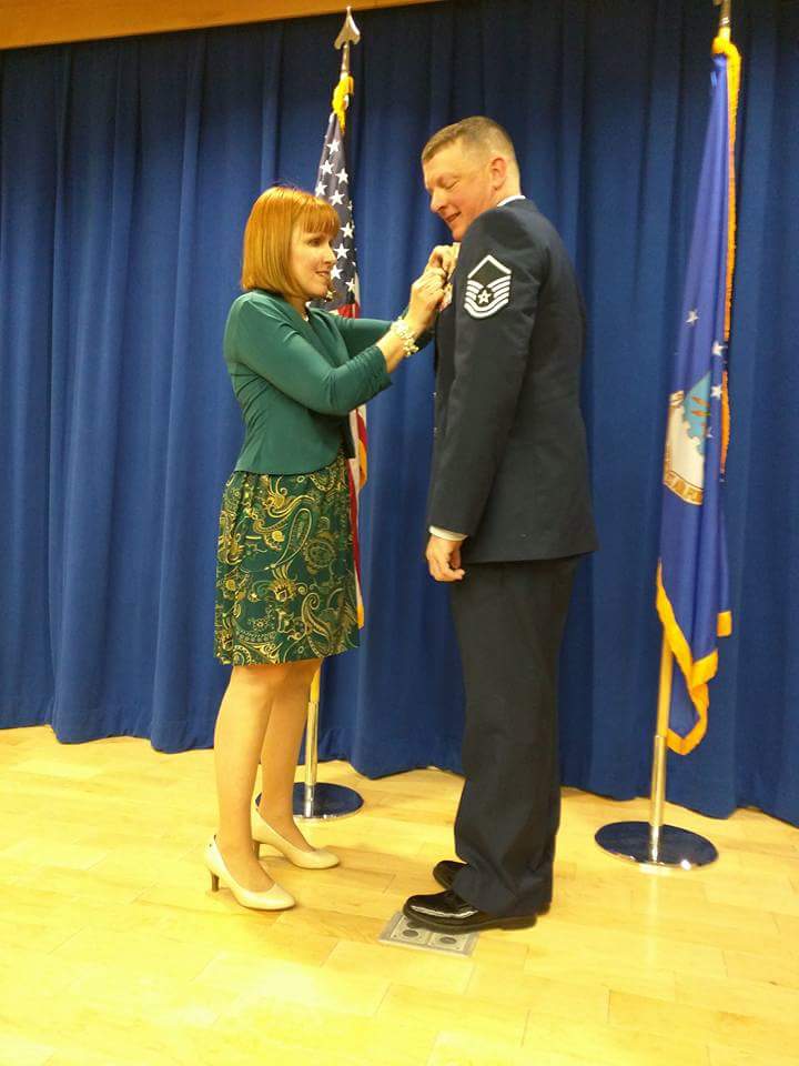 A woman pinning a pin onto a man in an Air Force uniform.